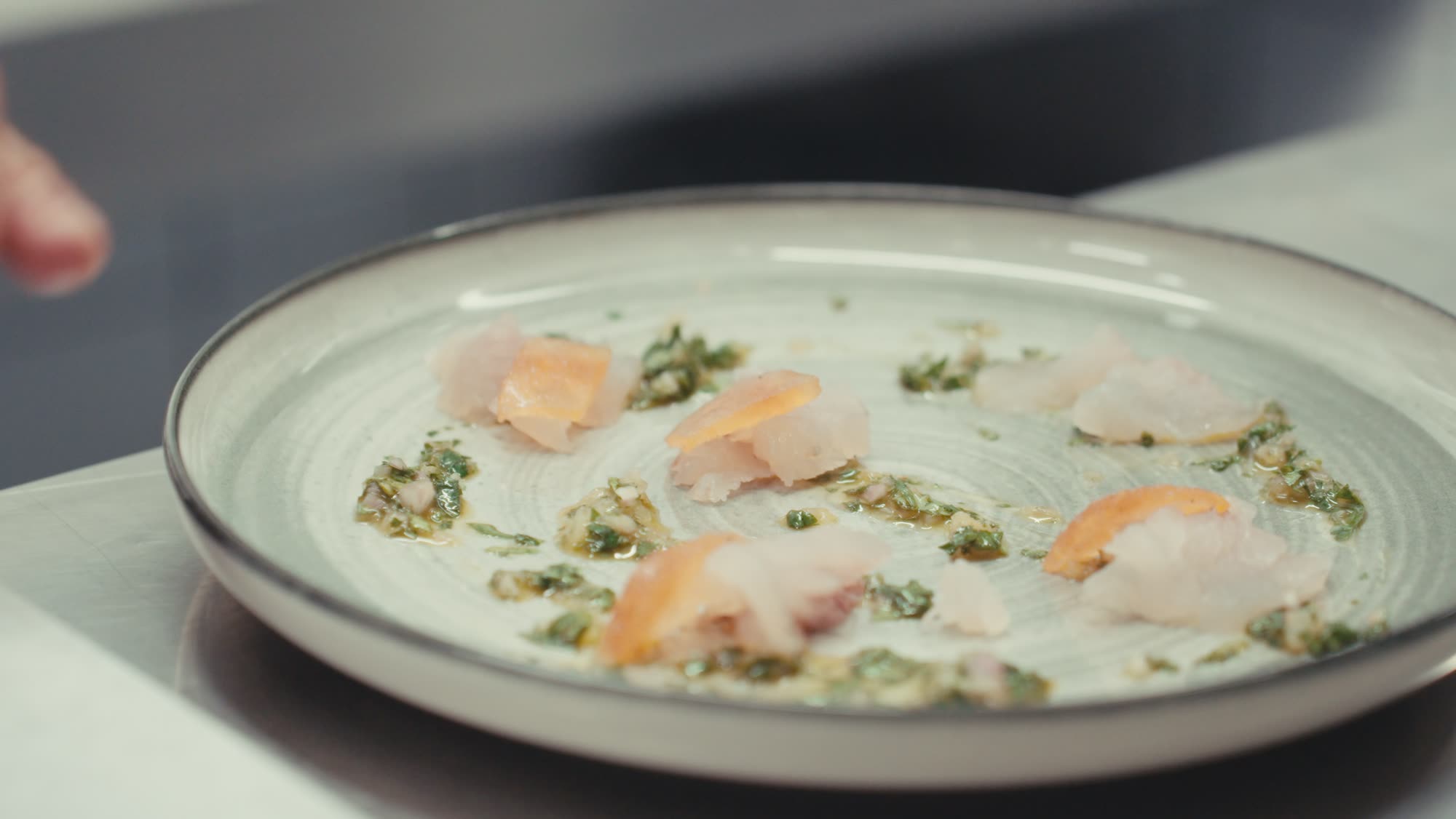 Le chef dresse une assiette de poisson cru aux herbes et fleurs