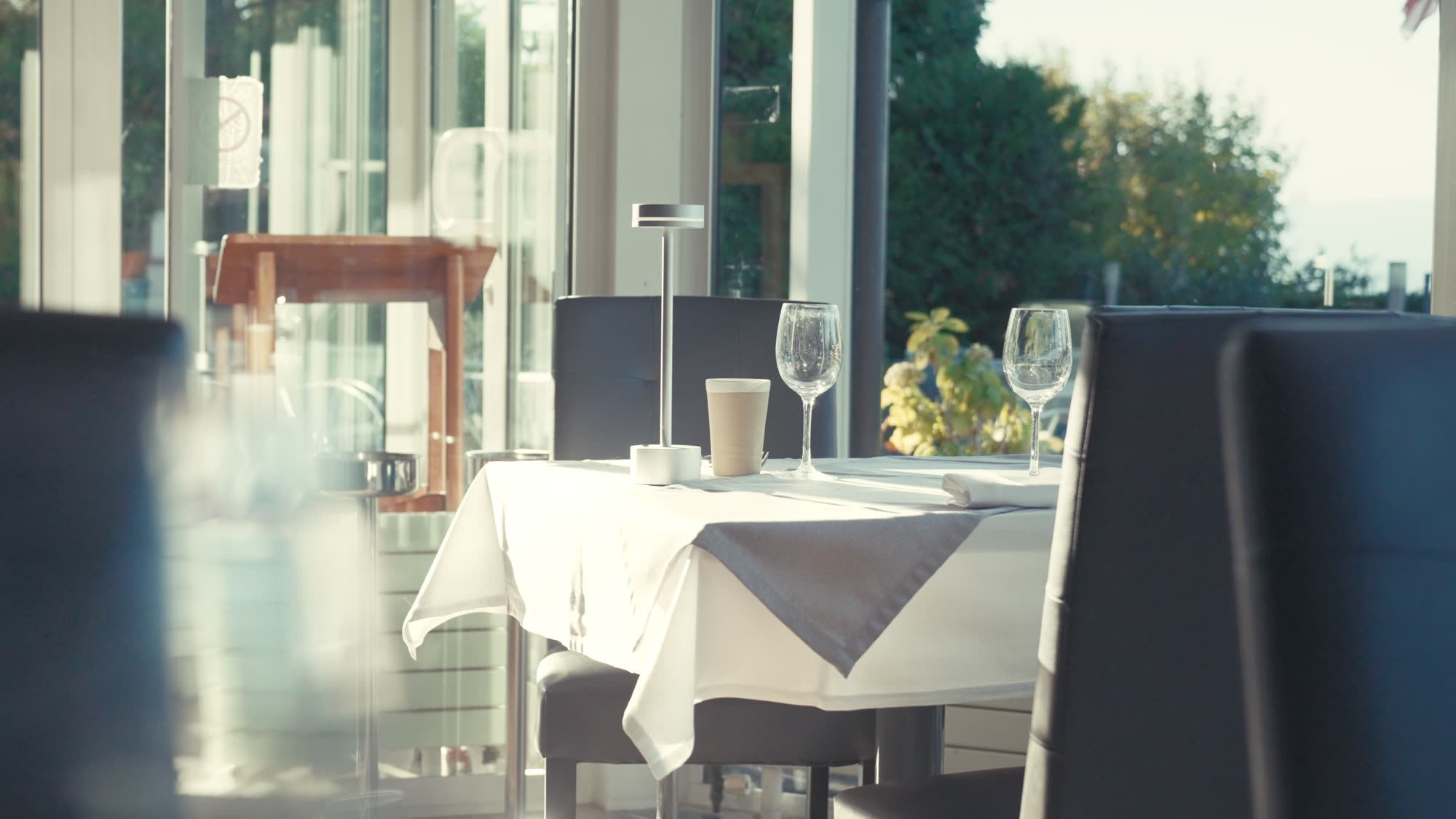 La salle lumineuse du restaurant, tables dressées face aux baies vitrées